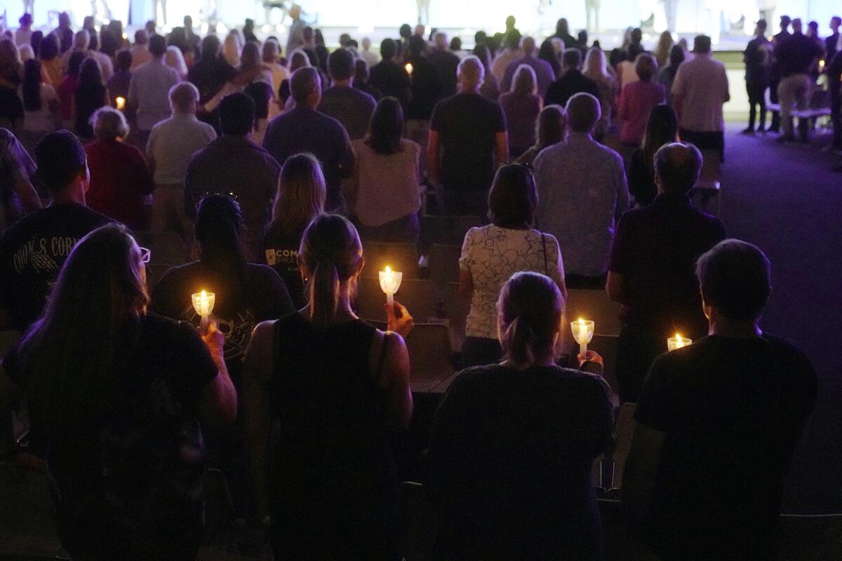People hold lighted candles as they join in a prayer vigil in the dark