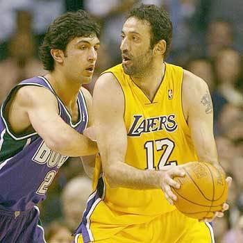 Los Angeles Lakers center Vlade Divac prepares to pass the ball as Milwaukee Bucks forward Zaza Pachulia defends him in the first half. It was Divac's first time playing for the Lakers this season after acquiring him as a free agent from the Sacramento Kings.