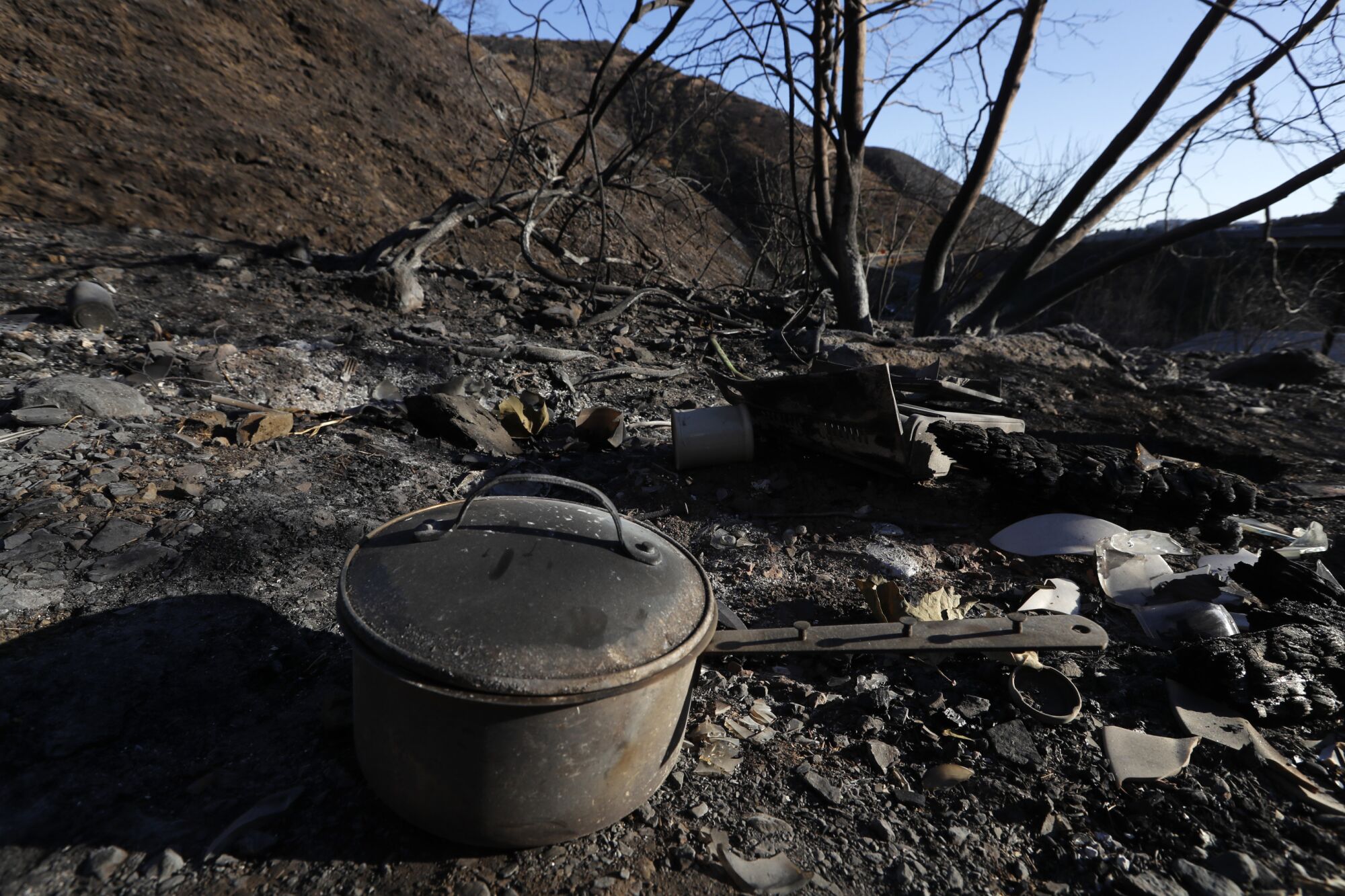 Amid scorched debris, a cooking pot sits in the foreground