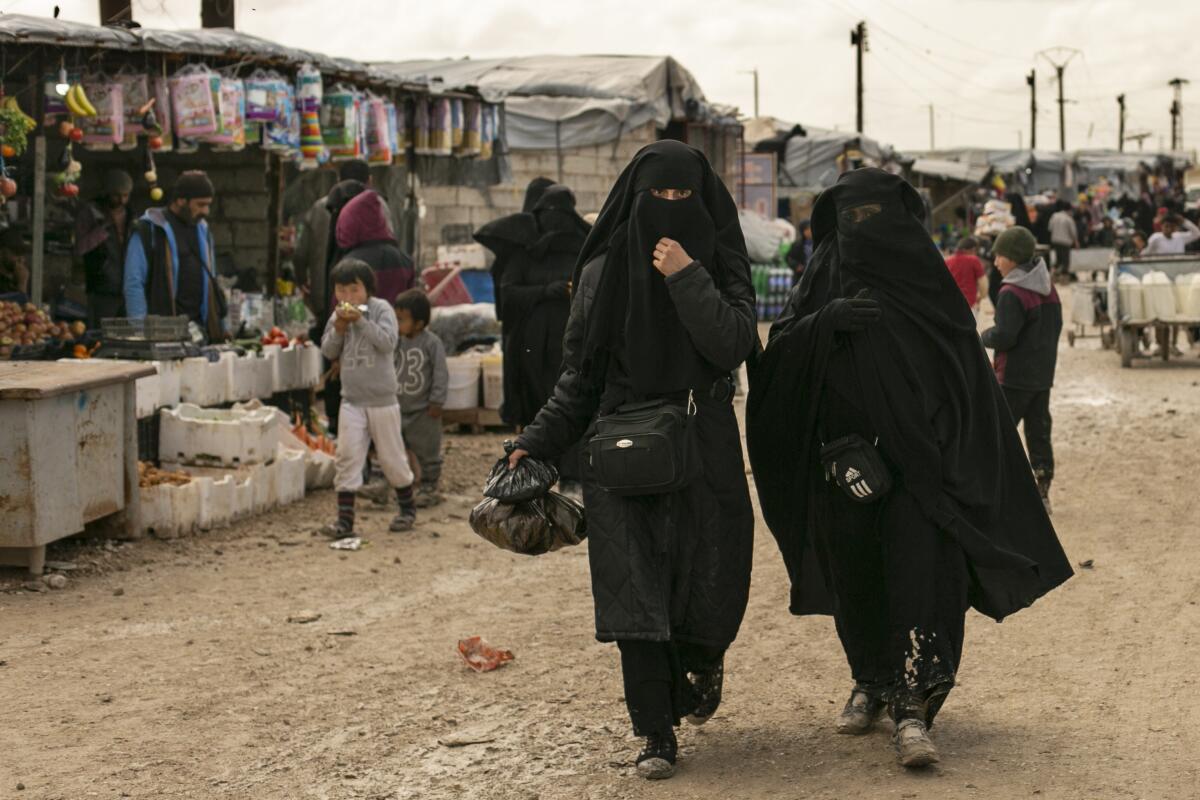 archivo - Dos mujeres compran en el mercado del campamento de al-Hol, 