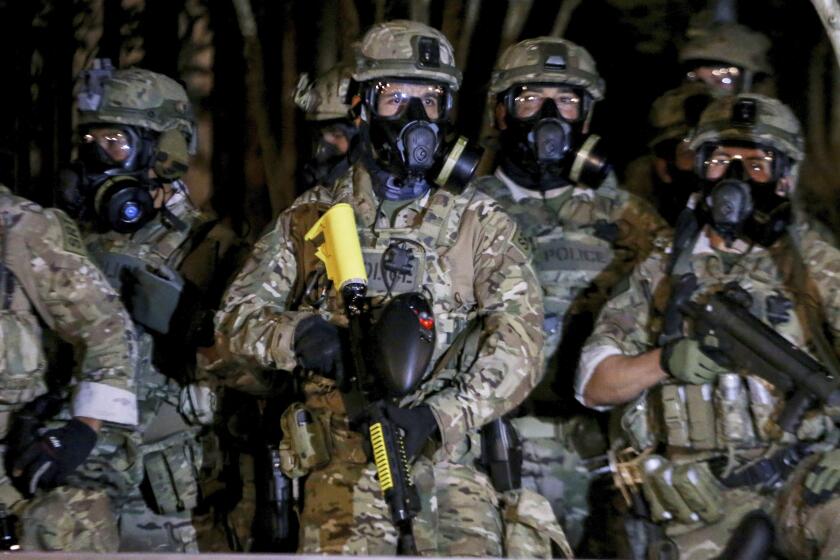 Police stand as protesters gather during a demonstration, Thursday, July 16, 2020 in Portland, Ore. Federal officers deployed tear gas and fired less-lethal rounds into a crowd of protesters late Thursday. The actions came just hours after the head of the Department of Homeland Security called the protesters “violent anarchists.” (Beth Nakamura/The Oregonian via AP)