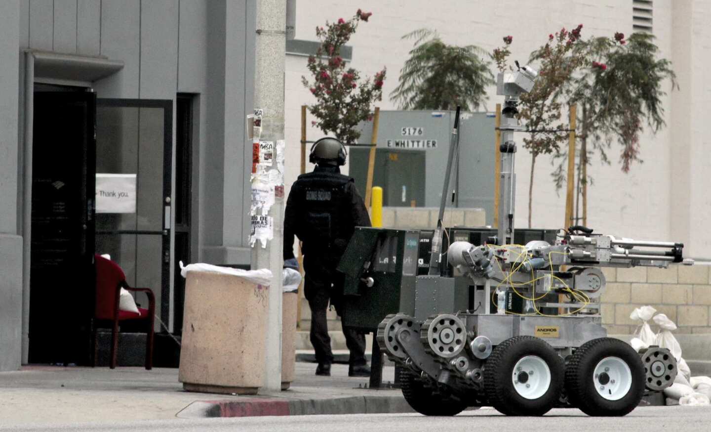 The L.A. County Sheriff's Department bomb squad was called to a Bank of America branch where a robbery occurred Wednesday morning in East Los Angeles. A manager at the bank was strapped with an apparent explosive device and forced to help two men rob her own bank. She followed instructions to throw the money out the bank's door. The robbers escaped.