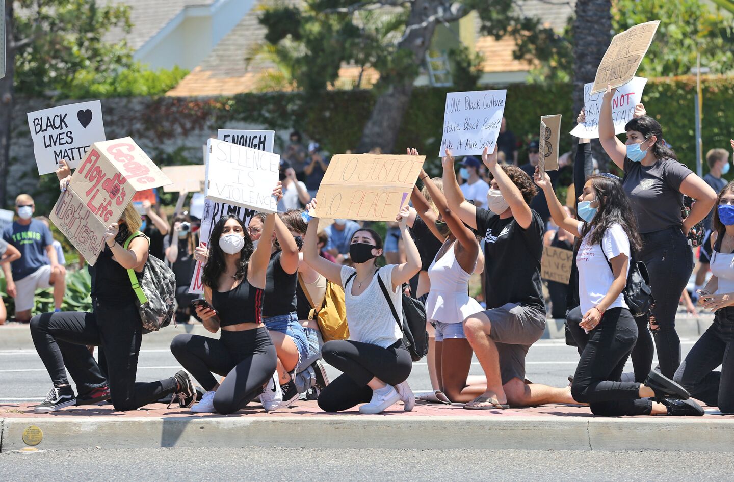 Protesters take a knee on a traffic island at the intersection of MacArthur Boulevard and Coast Highway during a Black Lives Matter protest in Newport Beach on Wednesday.