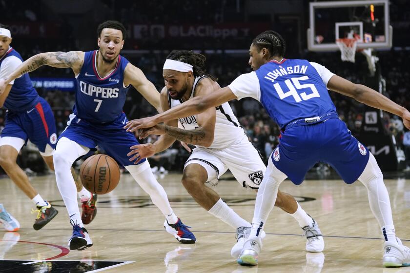 Brooklyn Nets' Patty Mills, center, cuts between Los Angeles Clippers' Keon Johnson, right, and Amir Coffey during first half of an NBA basketball game Monday, Dec. 27, 2021, in Los Angeles. (AP Photo/Jae C. Hong)
