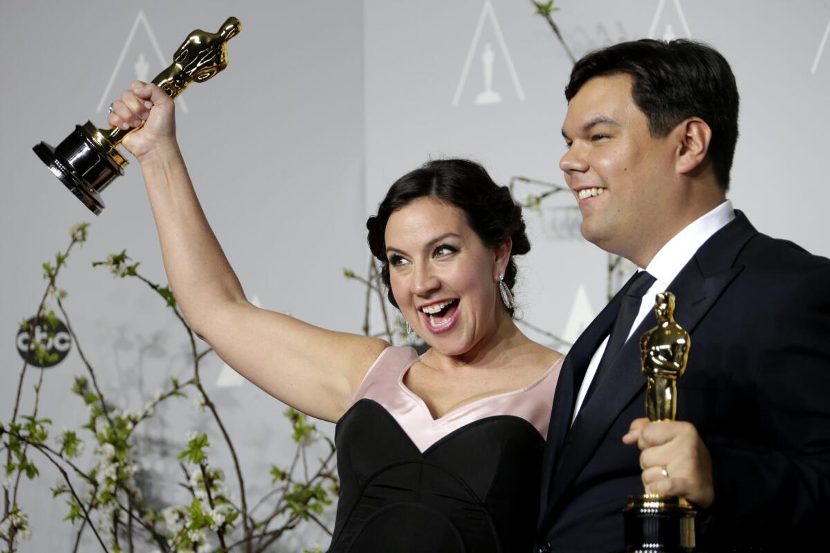 Kristen Anderson-Lopez and Robert Lopez show off their Oscars at the 86th Academy Awards at the Dolby Theatre.
