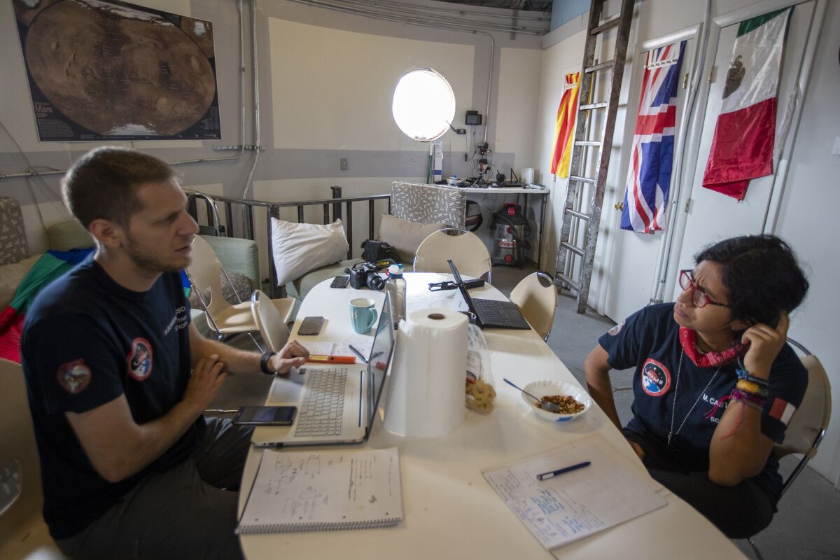 Italian engineer Paolo Guardabasso, left, confers with Peruvian commanding officer and biologist Marlen Castillo, right, inside the crew hub. (Brian van der Brug / Los Angeles Times)