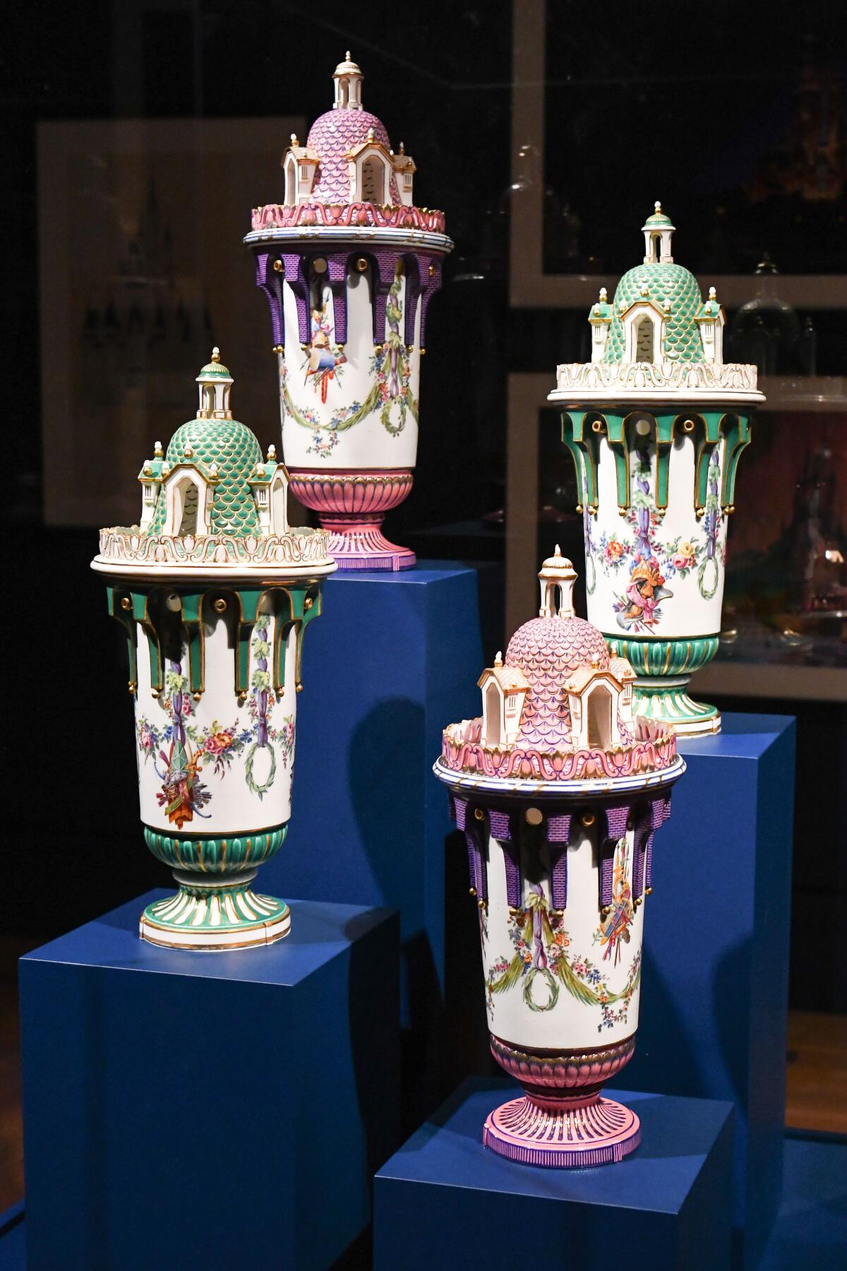 Ornate vases arranged on plinths are shown in candy shades of pink, purple and green.
