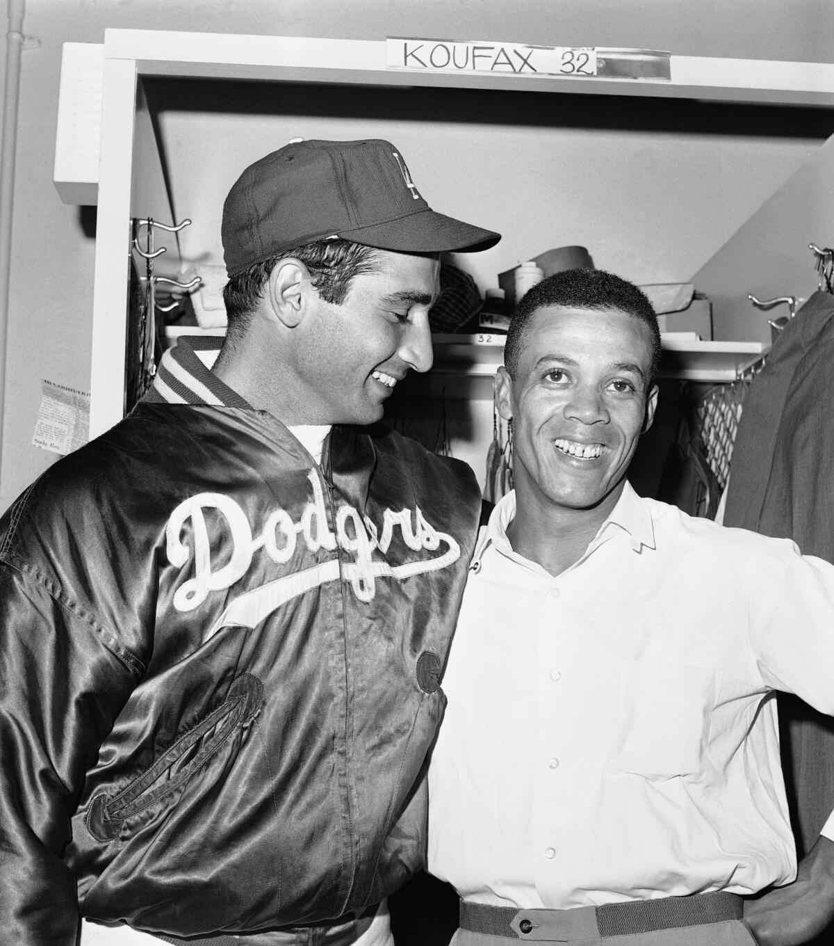 Sandy Koufax smiles at Maury Wills while the two stand together in the locker room.