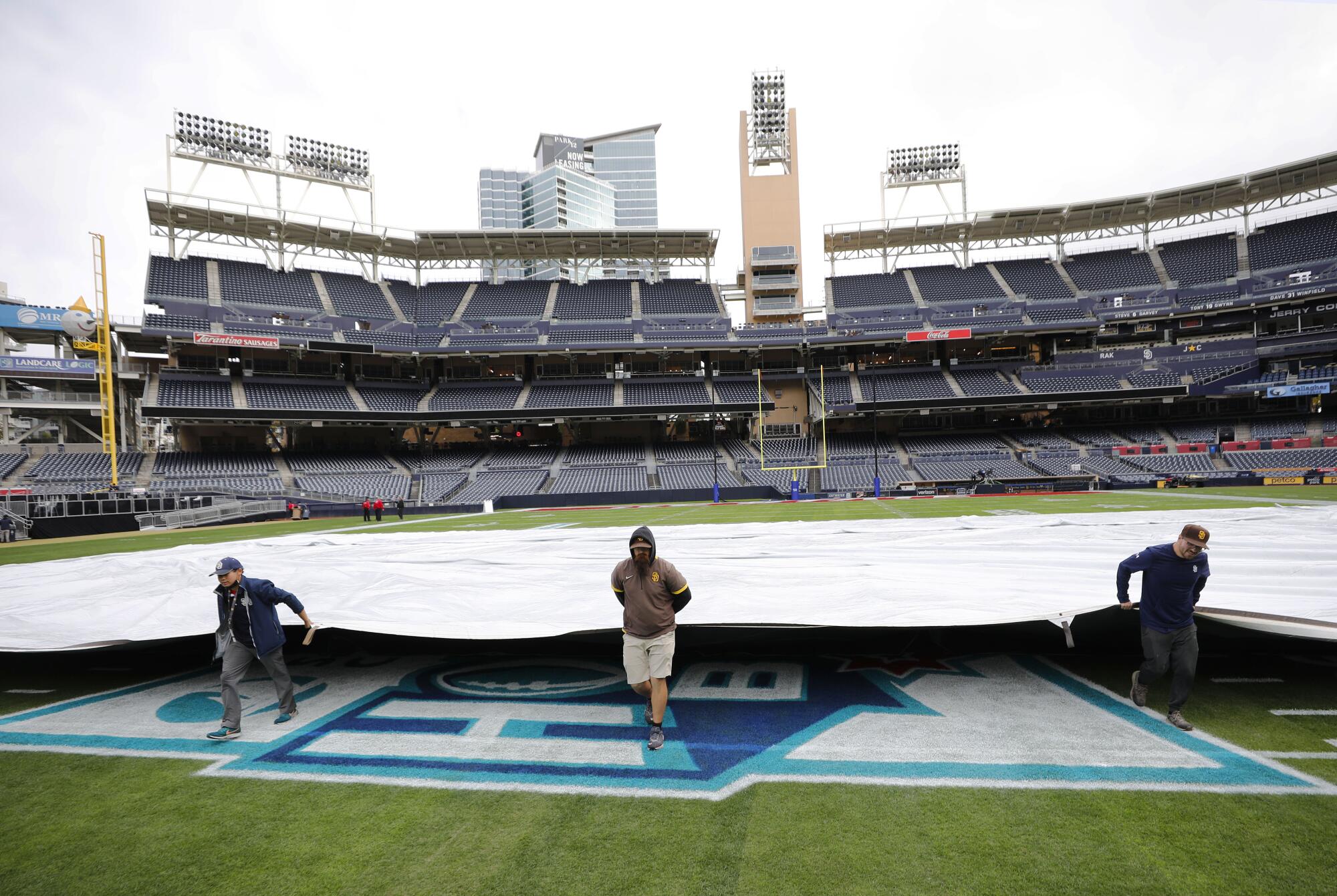 Workers cover the field with a tarp at Petco Park after the Holiday Bowl was cancelled. Rain was expected for the evening