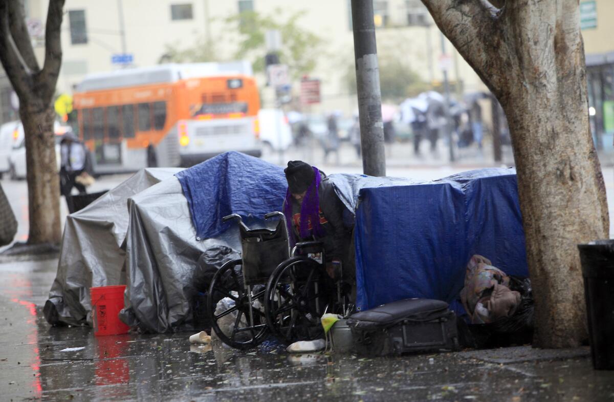 A woman emerges from her tent outside the Union Rescue Mission on skid row in Los Angeles.