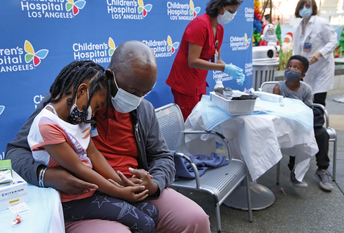 Samuel Alleyne comforts 5-year-old daughter Alahna before it’s her turn to get a COVID-19 shot.