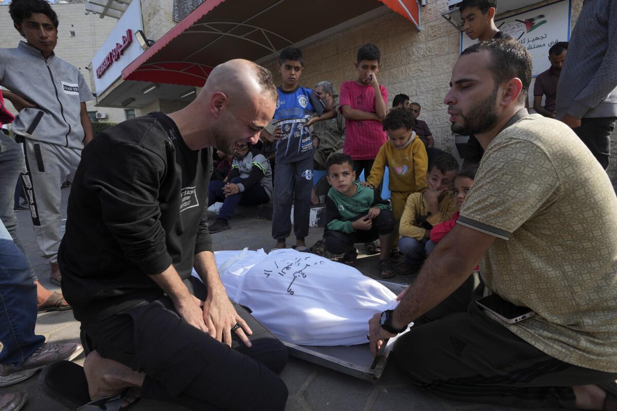 Palestinos lloran sobre el cuerpo de su padre, quien murió en un bombardeo israelí en la Franja 