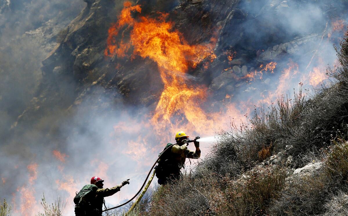 Firefighters battle a spot fire along Soledad Canyon Road near Agua Dulce on Tuesday.