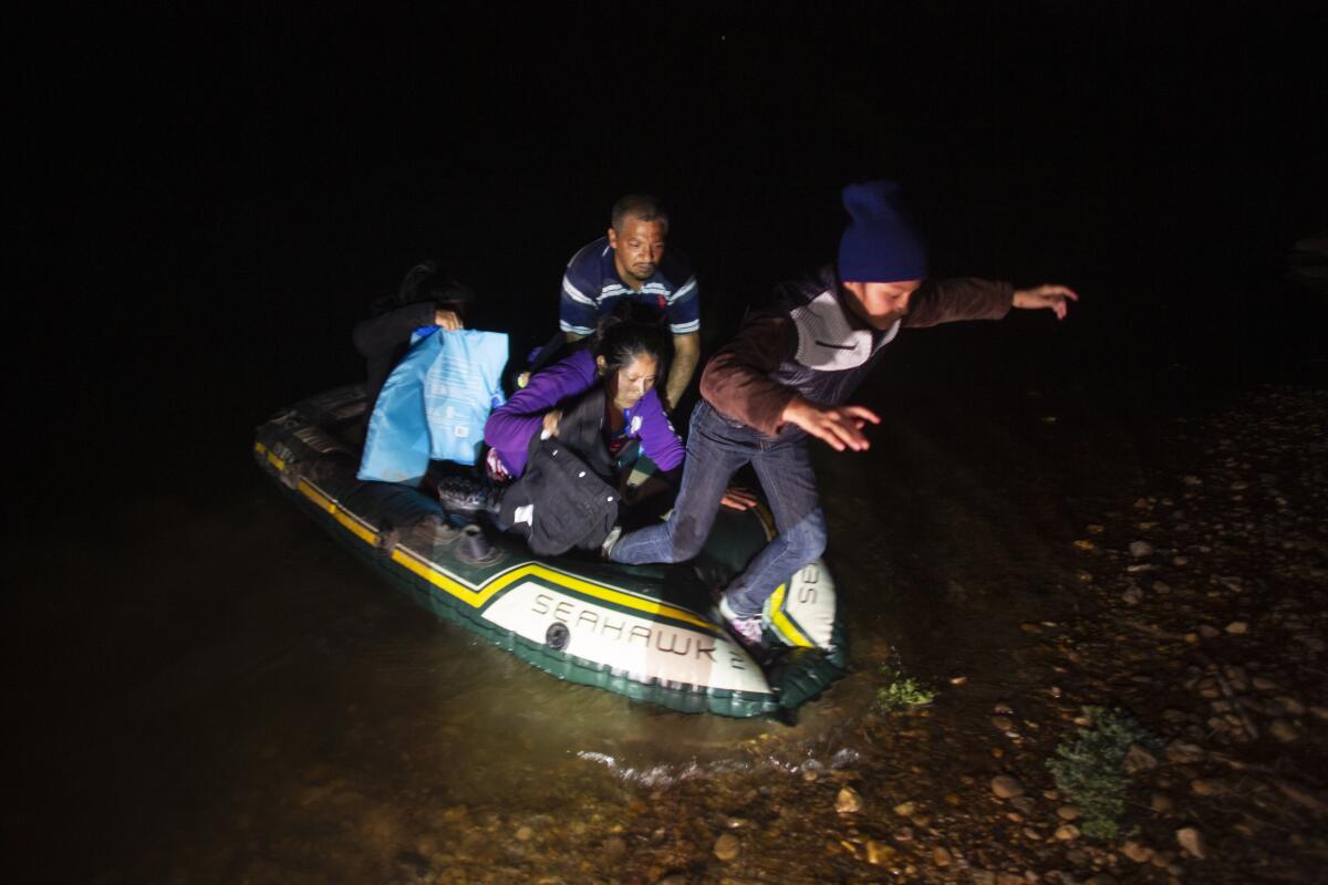 Migrantes desembarcan de un bote inflable con el que cruzaron el río Bravo 