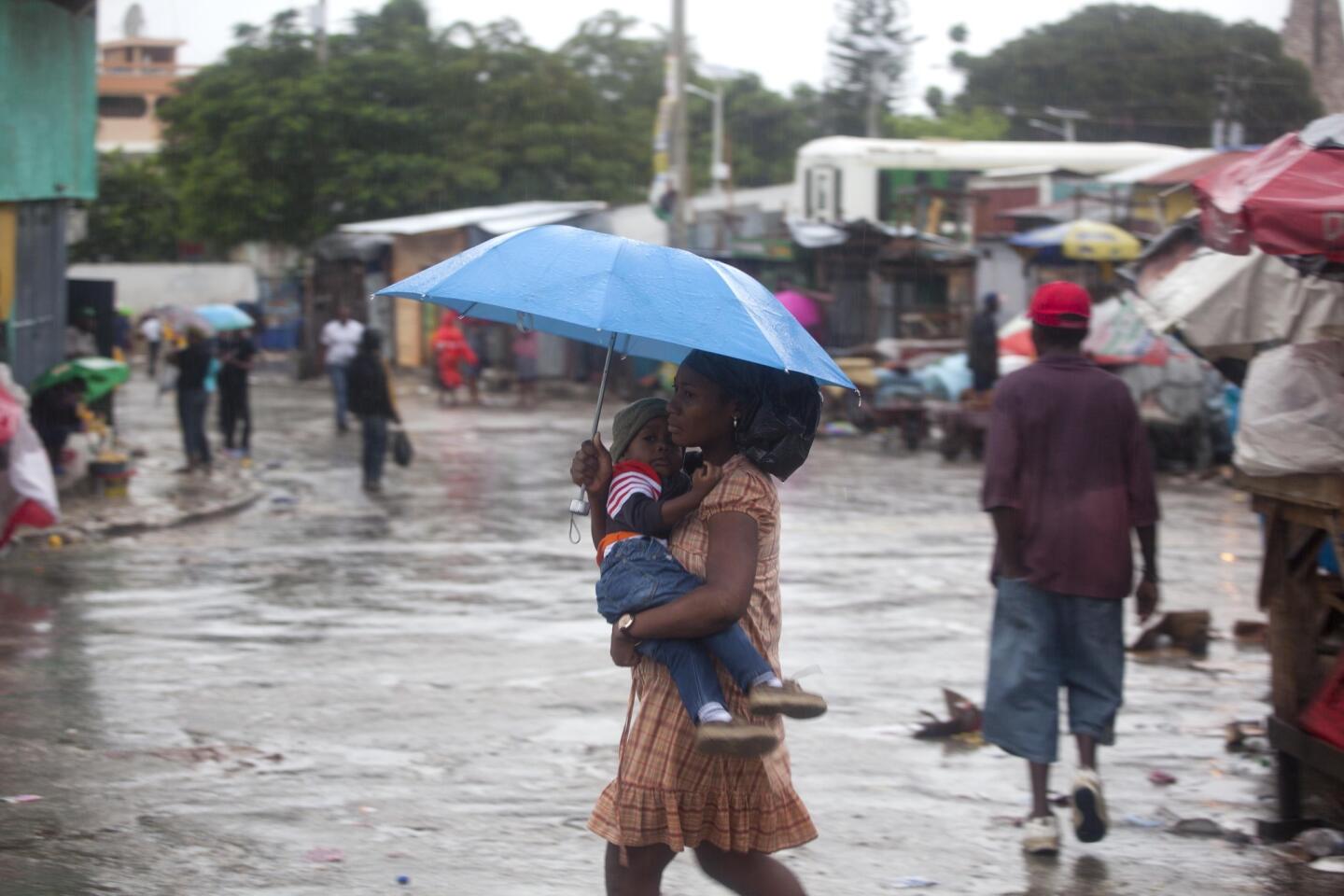 A woman carrying a child walks in the rain triggered by Hurricane Matthew in Port-au-Prince, Haiti, on Oct. 4, 2016.