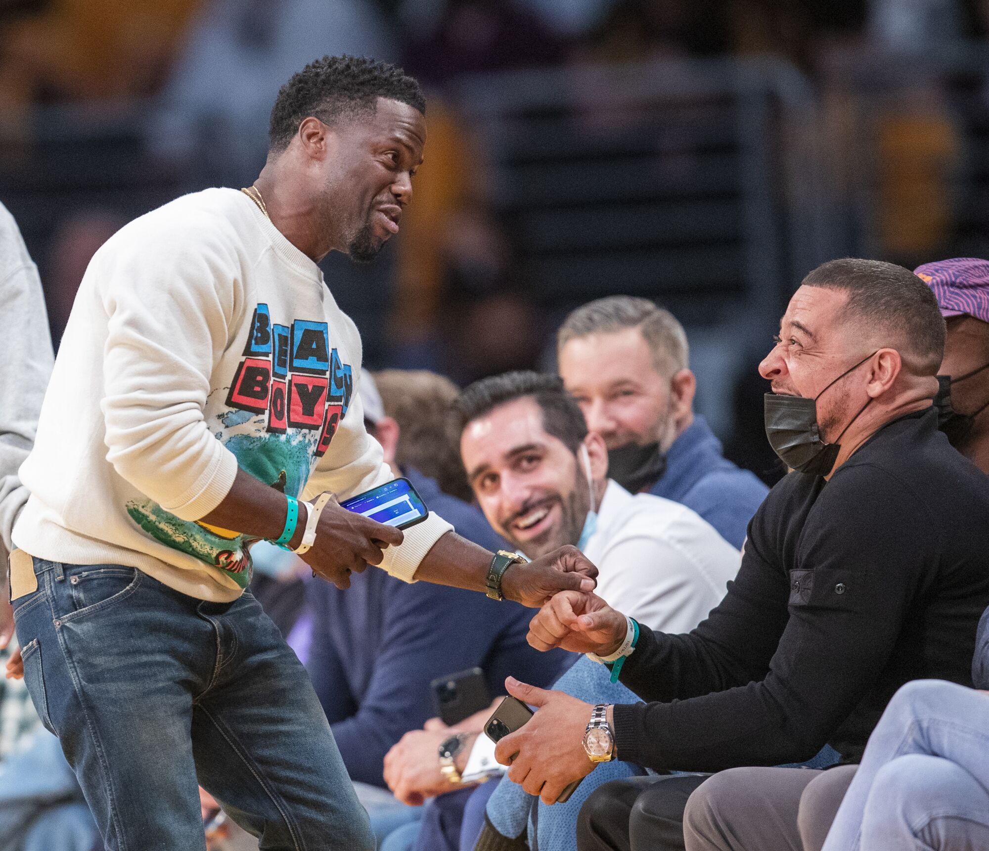 Kevin Hart fistbumps a masked man at the Lakers game