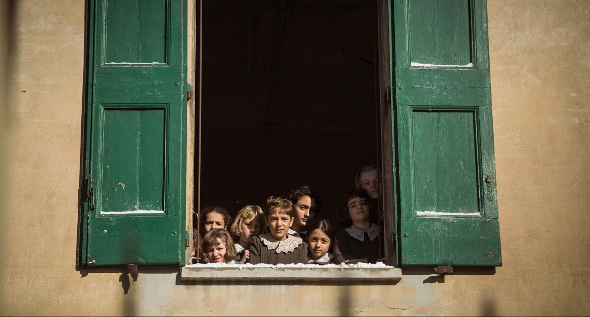 Young girls gather at window to look out in Italy during World War II.