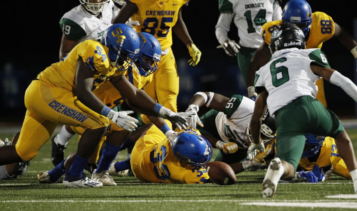Crenshaw's Michael Wilson (54) and Jamouri Leonard (52) reach in to grab a fumble by Dorsey running back Harrison Allen.