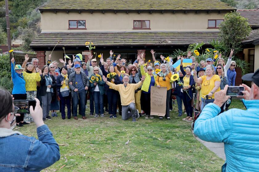 Supporters pose for a OLaguna Stands with UkraineO group photo that will be circulated on social media to raise awareness about the crisis unfolding overseas. Laguna Beach resident Denny Freidenrich, center, invited the public to assemble outside Laguna Beach City Hall on Thursday morning.