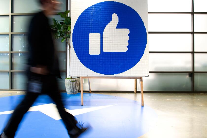 (FILES) In this file photo taken on October 23, 2019 a Facebook employee walks by a sign displaying the "like" sign at Facebook's corporate headquarters campus in Menlo Park, California. - President Donald Trump has been on a social media ad spending spree for his 2020 re-election campaign, but he's about to endure a massive digital counterattack. His opponents are rushing in with multimillion-dollar efforts to prevent him from dominating the web, even as the rules of the main platforms are in flux. Trump has spent more than $30 million on Facebook and Google since May 2018. His aggressive ads have spurred activists to pressure key sites to better police political misinformation or even ban campaign ads altogether, as Twitter has done. The digital battleground is expected to be expensive for candidates and, some say, crucial for their prospects. (Photo by Josh Edelson / AFP) (Photo by JOSH EDELSON/AFP via Getty Images) ** OUTS - ELSENT, FPG, CM - OUTS * NM, PH, VA if sourced by CT, LA or MoD **