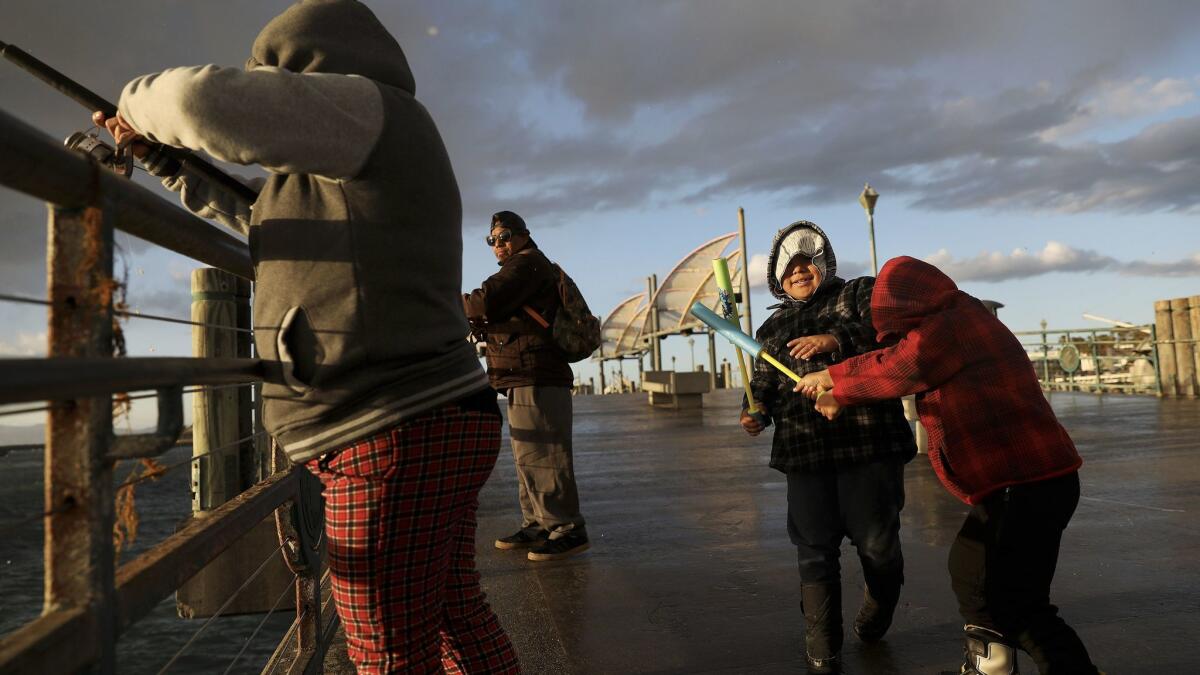 David Matias, 5, right, of Valencia, plays with his brother Angel, 7, as their parents Connie Lopez, left, and Herman Matias fish off the Redondo Beach Pier on Monday.