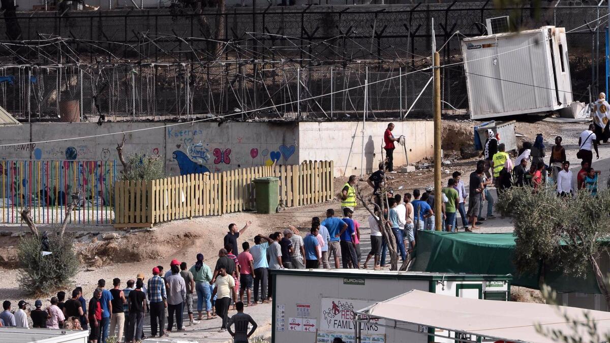 Migrants line up next to burned tents at the Moria camp on the Greek island of Lesbos after a fire on Sept. 20, 2016.