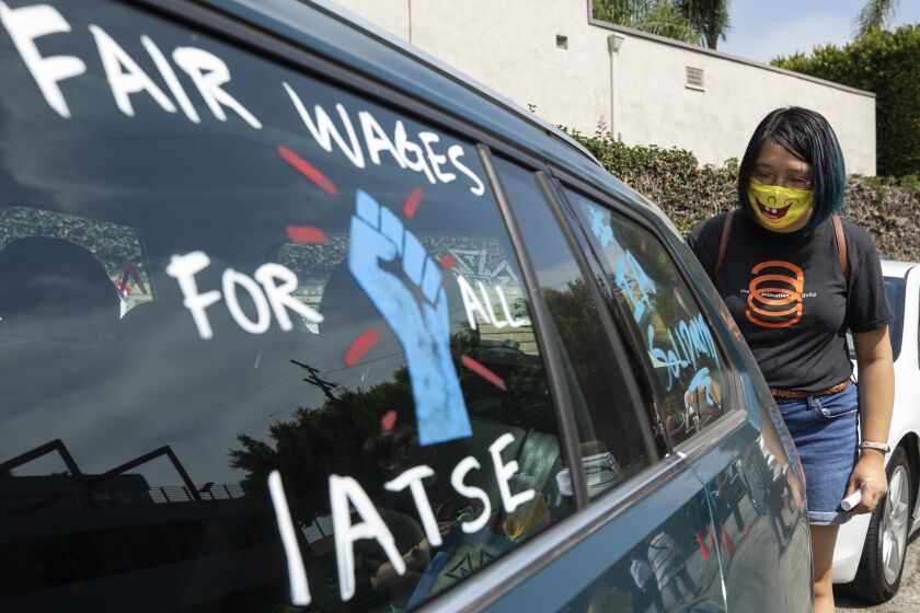 LOS ANGELES, CA - SEPTEMBER 26: Crystal Kan, a storyboard artist, draws pro-labor signs on cars of union members during a rally at the Motion Picture Editors Guild IATSE Local 700 on Sunday, Sept. 26, 2021 in Los Angeles, CA. Up to 60,000 members of the International Alliance of Theatrical Stage Employees (IATSE) might go on strike in the coming weeks over issues of long working hours, unsafe conditions, less pay from streaming companies and demand for better benefits. (Myung J. Chun / Los Angeles Times)