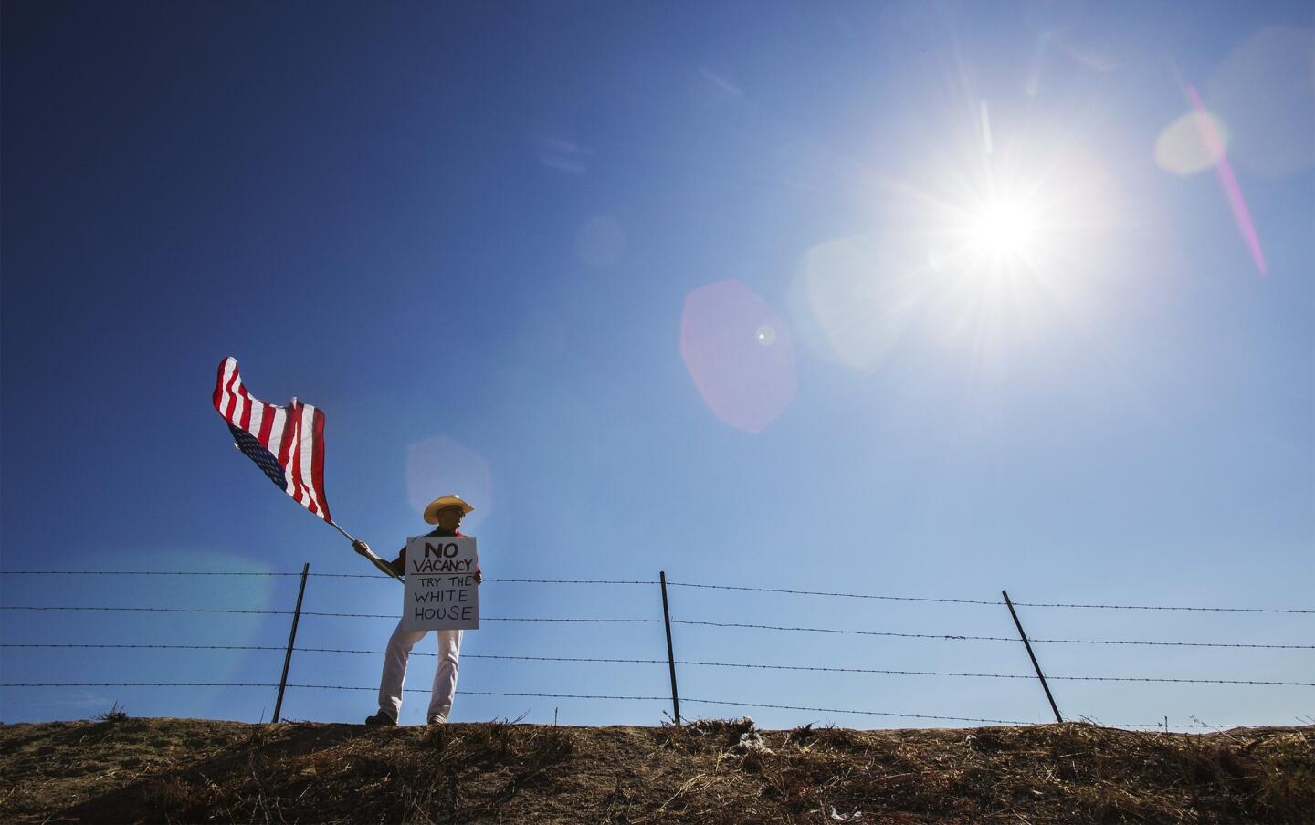 Protester William Satmary of Murrieta stands on a hill to keep a lookout for buses containing immigrant detainees.