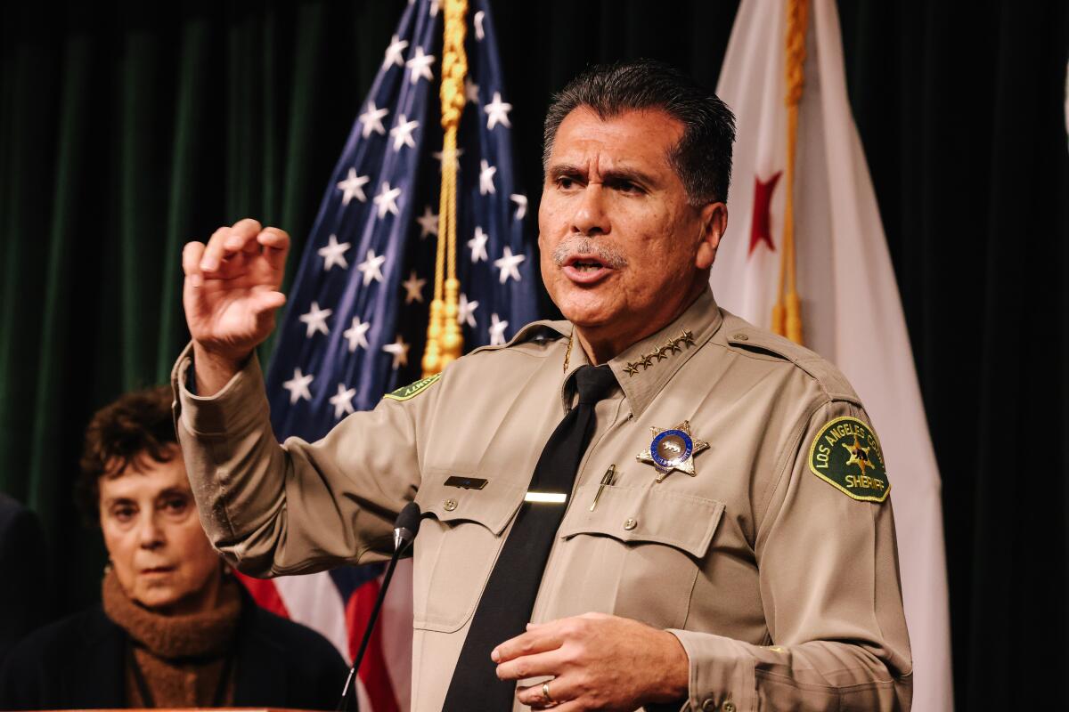 A man in a sheriff's uniform speaks into a microphone at a news conference