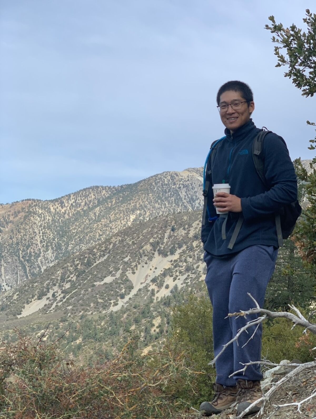 A hiker holds a cup of coffee in the mountains