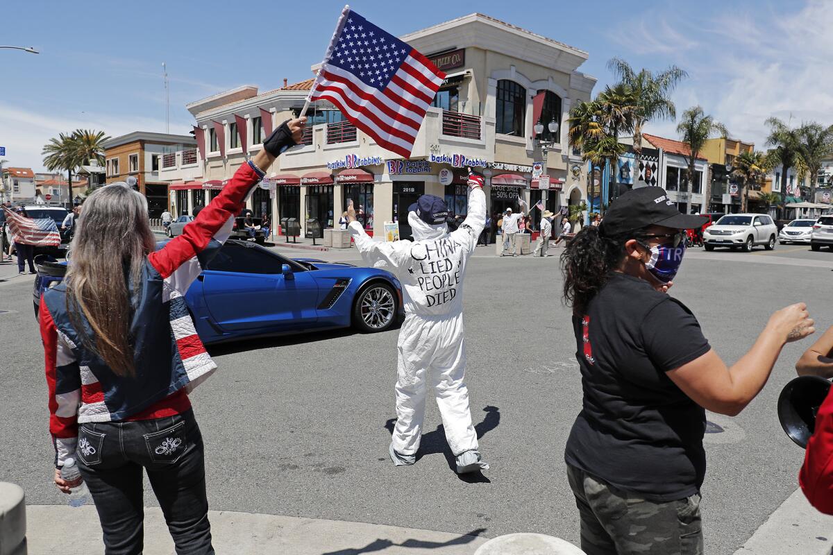 A message written on a man's back reads, "CHINA LIED PEOPLE DIED," as demonstrators crowd the intersection at Main Street and Walnut Avenue in downtown Huntington Beach on Friday.