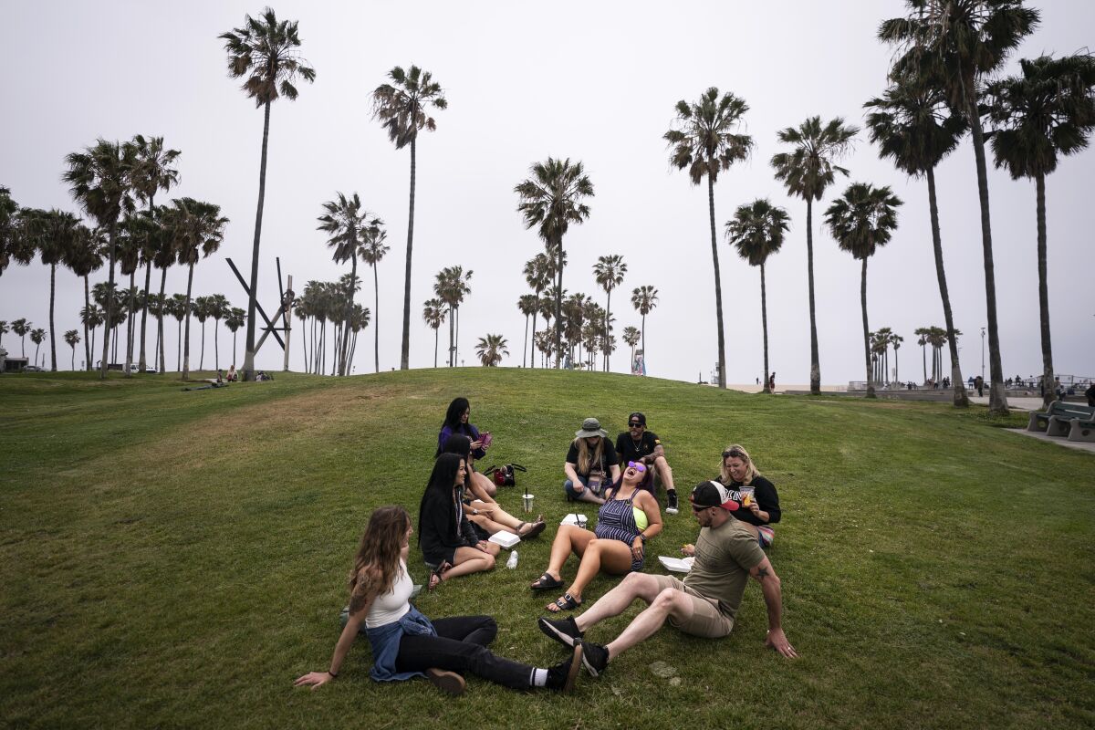 FILE - In this May 5, 2021, file photo, a group of friends, who said they are fully vaccinated for COVID-19, mingle on the beach in the Venice section of Los Angeles. COVID-19 deaths in the U.S. have tumbled to an average of just over 600 per day — the lowest level in 10 months — with the number of lives lost dropping to single digits in well over half the states and hitting zero on some days. (AP Photo/Jae C. Hong, File)
