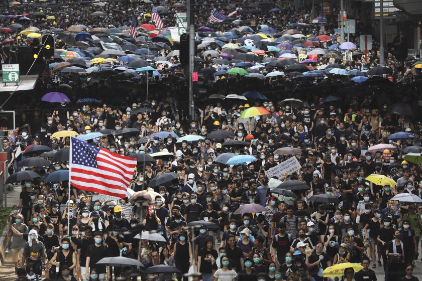 In this Sunday, July 28, 2019, file photo, protesters carry U.S. flags and placards during a protest march in Hong Kong. A sea of black-shirted protesters, some with bright yellow helmets and masks but many with just backpacks, marched down a major street in central Hong Kong on Sunday in the latest rally in what has become a summer of protest. (AP Photo/Vincent Yu, File)