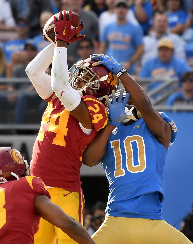USC defensive back Isaiah Langley intercepts a ball in the end zone in front of UCLA receiver Demetric Felton during the third quarter Saturday at the Rose Bowl.