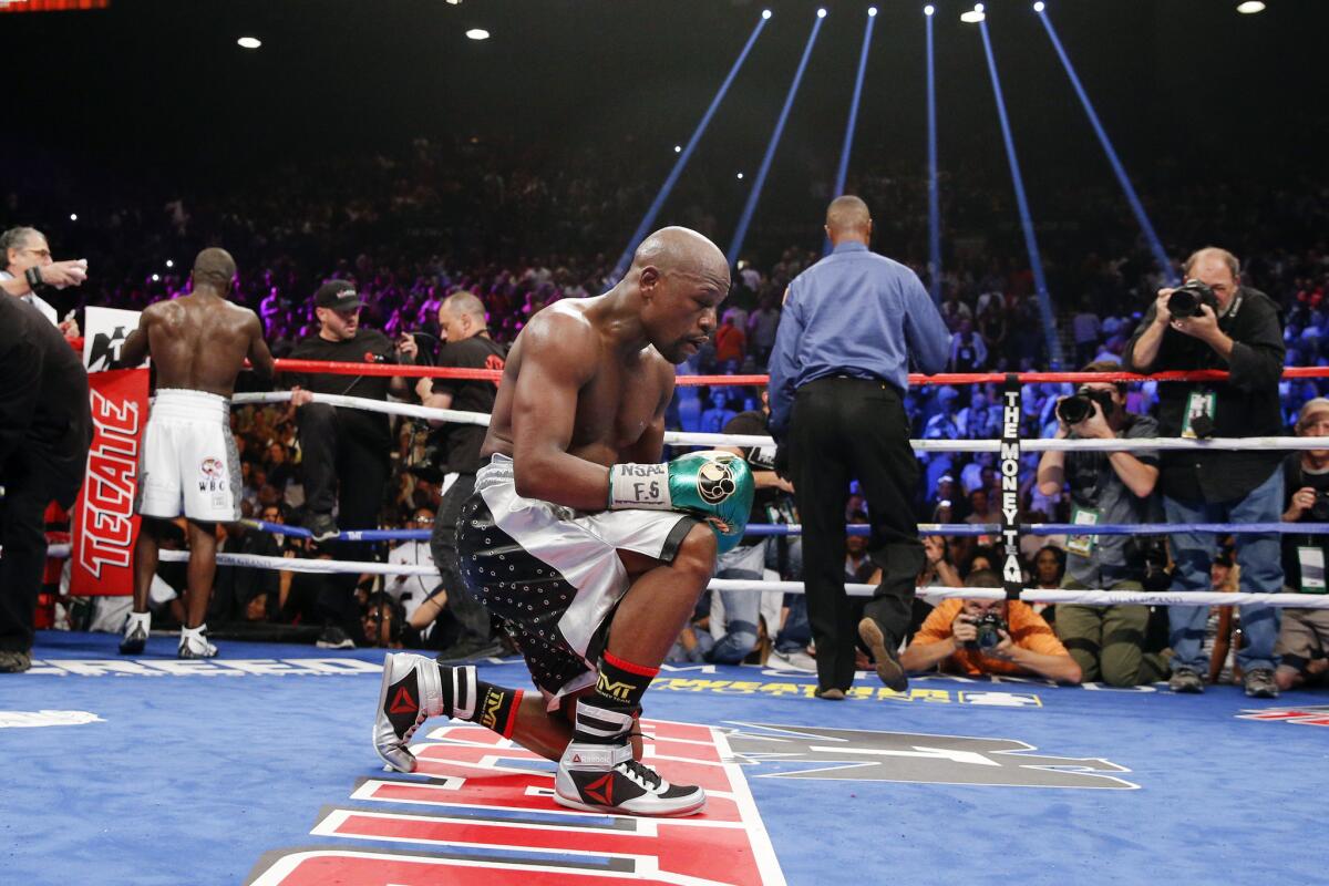Floyd Mayweather Jr. kneels at the end of his welterweight title fight against Andre Berto, left, Saturday, Sept. 12, 2015, in Las Vegas. (AP Photo/John Locher)