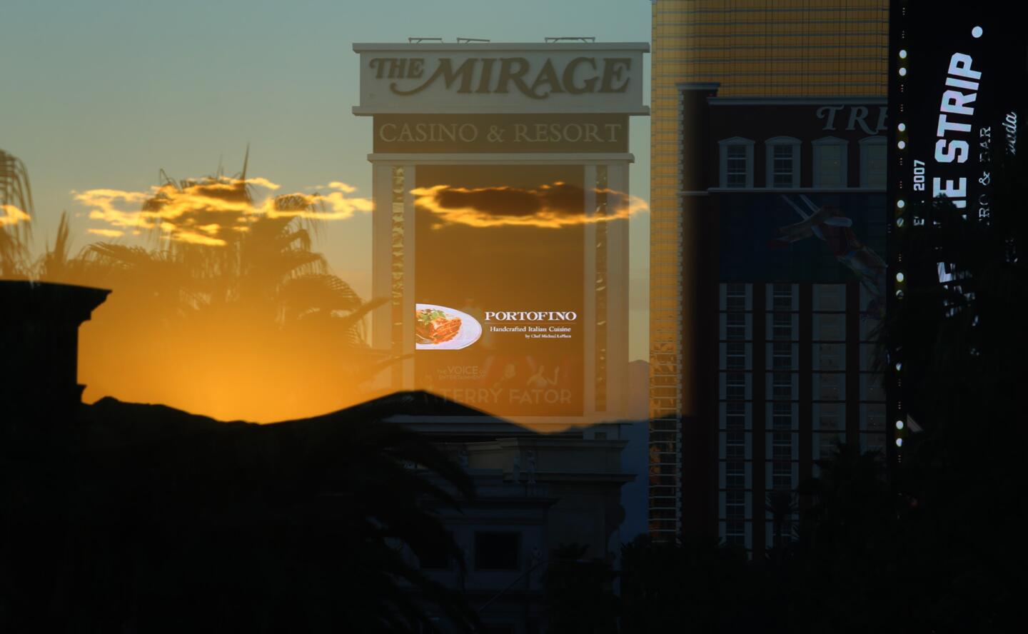 A sunset is reflected against the window of a pedestrian bridge, creating a mirage on the Mirage hotel and casino in Las Vegas. Known for bright lights and gambling tables, Vegas has also served as a literary inspiration.