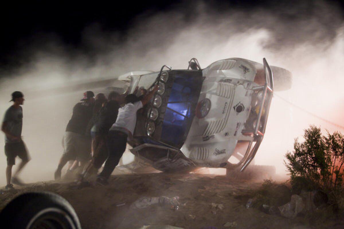In this Aug. 15, 2010, file photo, people push an overturned off-road race truck upright after it went out of control and ran into a crowd of spectators during a race in the desert outside Victorville. A settlement has been reached in the case.