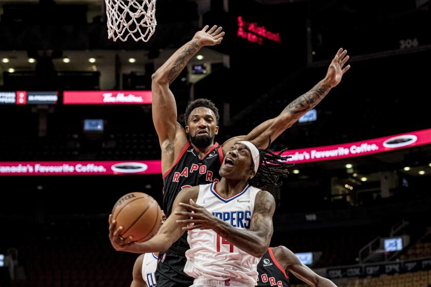Los Angeles Clippers guard Terance Mann (14) attempts a layup as Toronto Raptors center Khem Birch defends during the first half of an NBA basketball game Saturday, Dec. 31, 2021, in Toronto. (Chris Katsarov/The Canadian Press via AP)