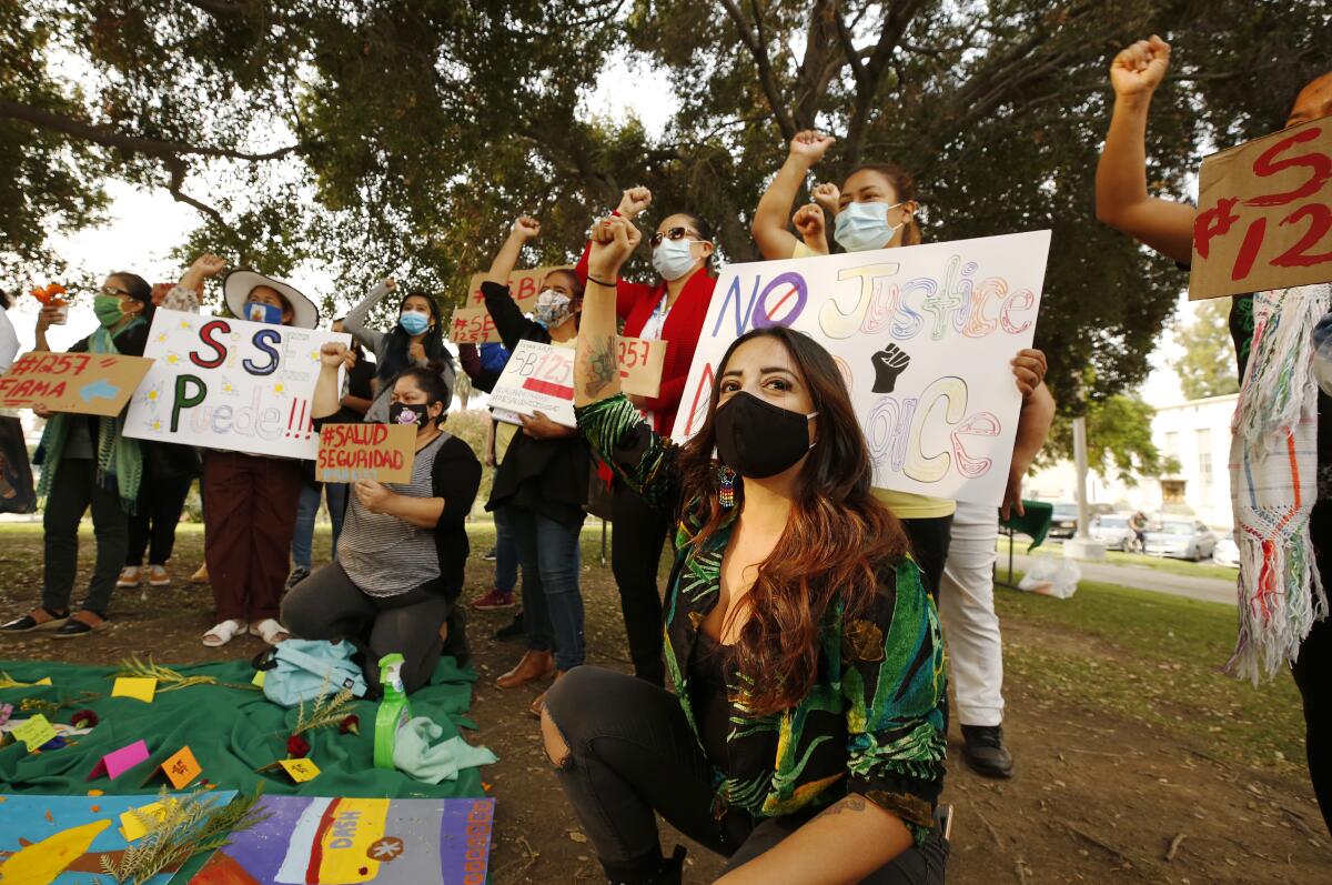 Women wearing masks raise their fists in a protest at a park