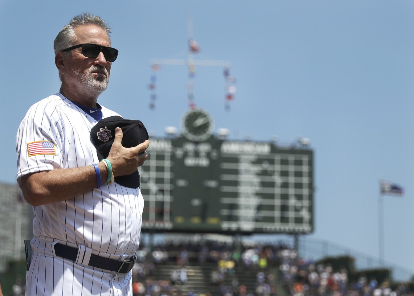 Chicago Cubs manager Joe Maddon stands for the national anthem before a baseball game against the Detroit Tigers Tuesday, July 3, 2018, in Chicago. (AP Photo/Charles Rex Arbogast)