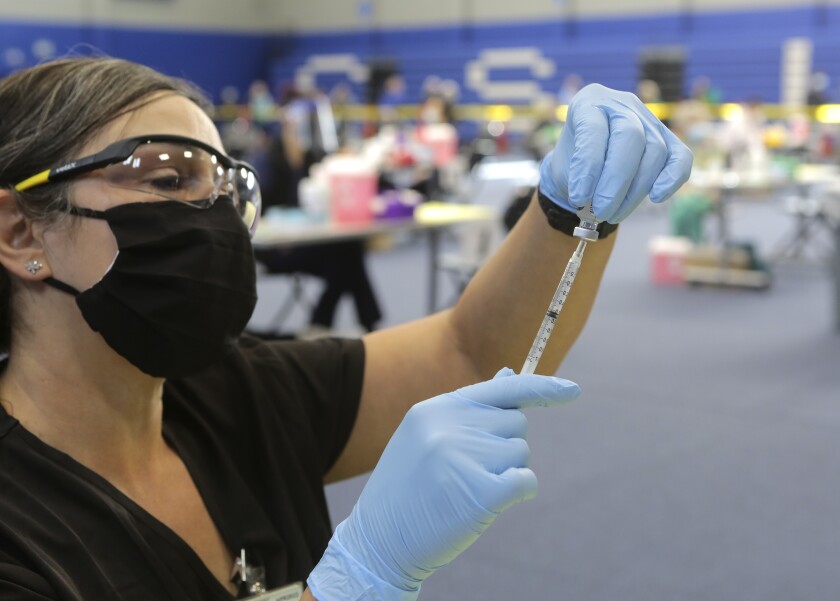 Dr. Edith Lederman fills a syringe with Pfizer vaccine at a vaccination super station at CSU San Marcos.