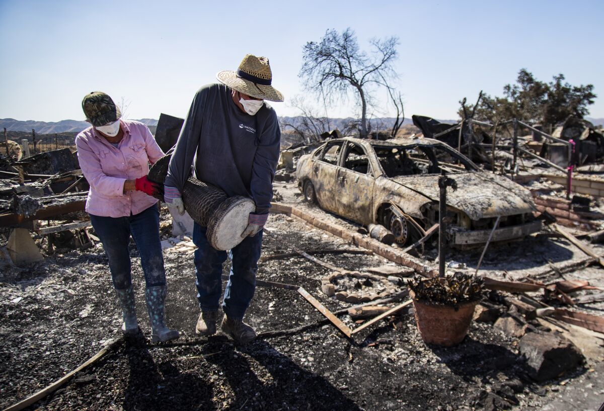 Judy Dorius,70, of San Diego and her brother Don Turner,62, of Phelen salvage a bird bath base from the burned ruins of the home where their mother Lois Arvickson, 89, died at the Villa Calimesa Mobile Home Park.