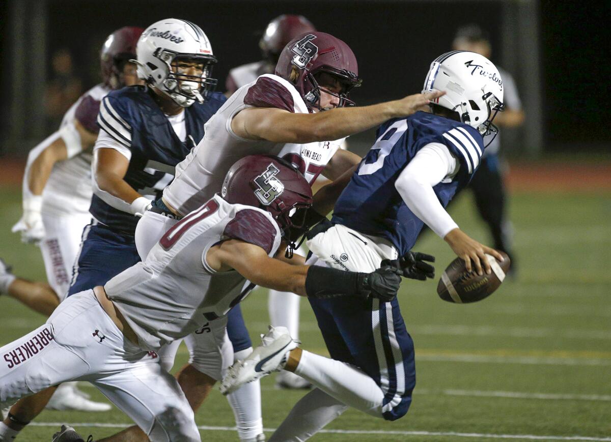 Laguna Beach defensive lineman Casey Mullennix and Skylar Schwarm (50) run down Northwood quarterback Edward Ma.