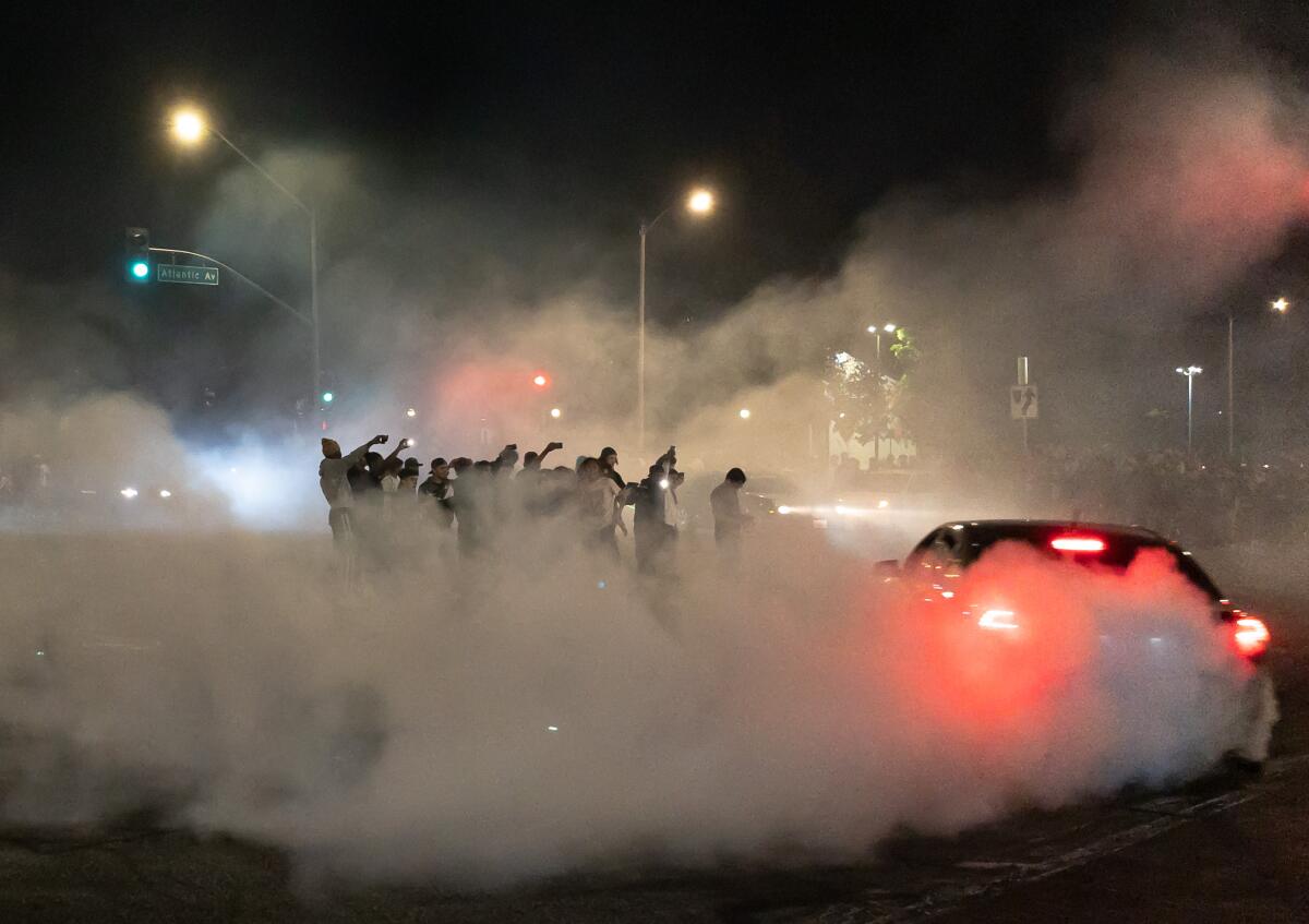 A car drifts around spectators gathered in the middle of an intersection during a street takeover in Compton on Aug. 14.