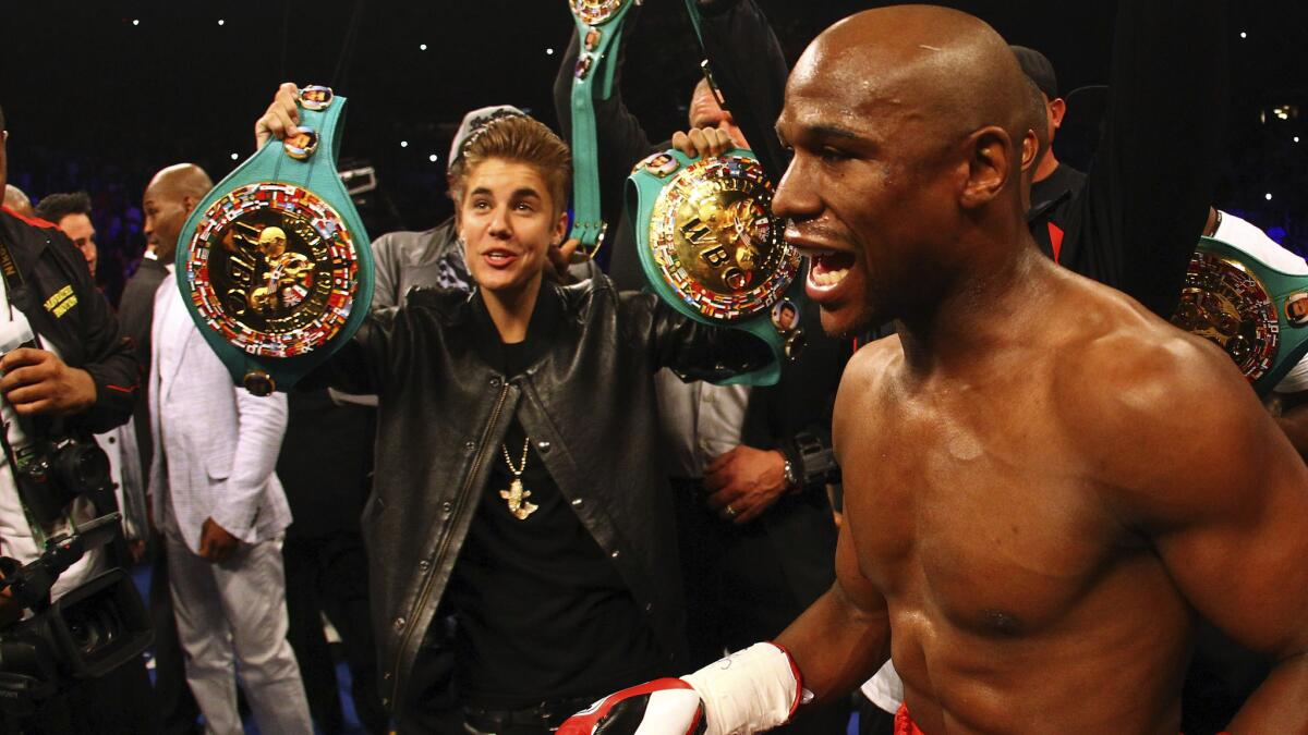 Recording artist Justin Bieber, left, holds up a pair of championship belts before Floyd Mayweather Jr.'s fight against Miguel Cotto at the MGM Grand in Las Vegas on May 5, 2012.