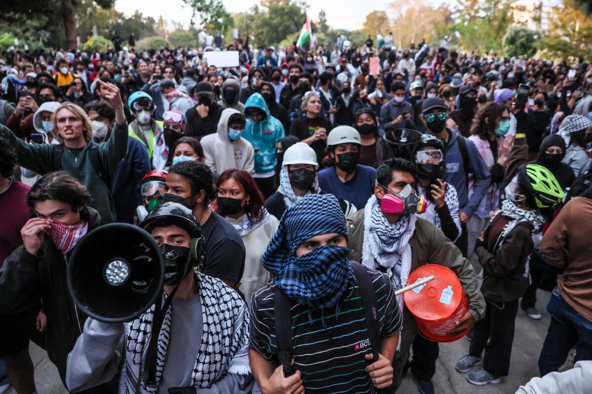 A protesting crowd, many with faces covered