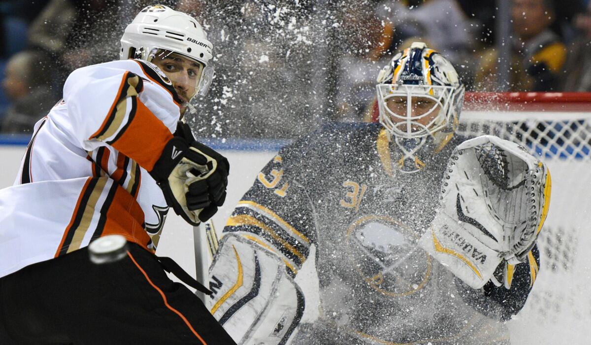 Anaheim Ducks left winger Andrew Cogliano, left, looks back at the incoming puck as Buffalo Sabres goaltender Chad Johnson braces for the shot during the second period on Thursday.