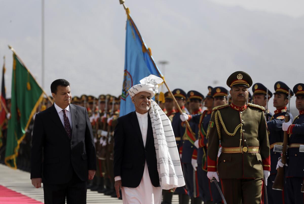 FILE - In this March 6, 2021 file photo, Afghan President Ashraf Ghani, center, inspects an honor guard during the opening ceremony of the new legislative session of the Parliament, in Kabul, Afghanistan. Afghanistan’s embattled president left the country Sunday, Aug. 15, 2021, joining his fellow citizens and foreigners in a stampede fleeing the advancing Taliban and signaling the end of a 20-year Western experiment aimed at remaking Afghanistan. (AP Photo/Mariam Zuhaib, File)