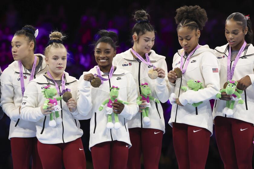 Team USA look at their medals as Simone Biles smiles, third left, after the women's team final at the Artistic Gymnastics World Championships in Antwerp, Belgium, Wednesday, Oct. 4, 2023. (AP Photo/Geert vanden Wijngaert)