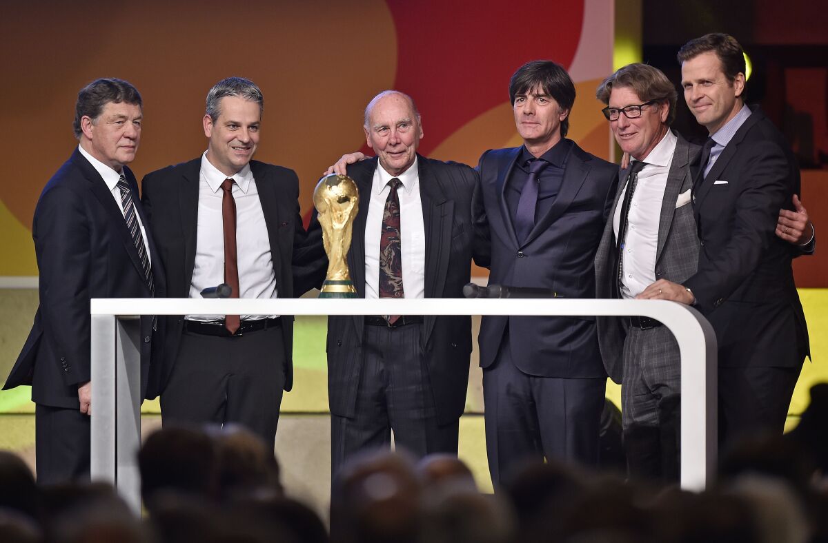 FILE - Legendary 1954 world champion Horst Eckel, center, poses behind the trophy with coach legend Otto Rehagel, museum director Manuel Neukirchner, German national head coach Joachim Loew, 1980 European champion keeper Harald Schumacher and team manager Olvier Bierhoff , from left, at the opening of the German football museum in Dortmund, Germany, Friday, Oct. 23, 2015. The last surviving member of West Germany’s 1954 World Cup-winning team Horst Eckel has died at the age of 89. Eckel was one of only two West German players to play in every match as the team completed the “Wonder of Bern” by beating pre-tournament favorite Hungary 3-2 in the final. (AP Photo/Martin Meissner, File)